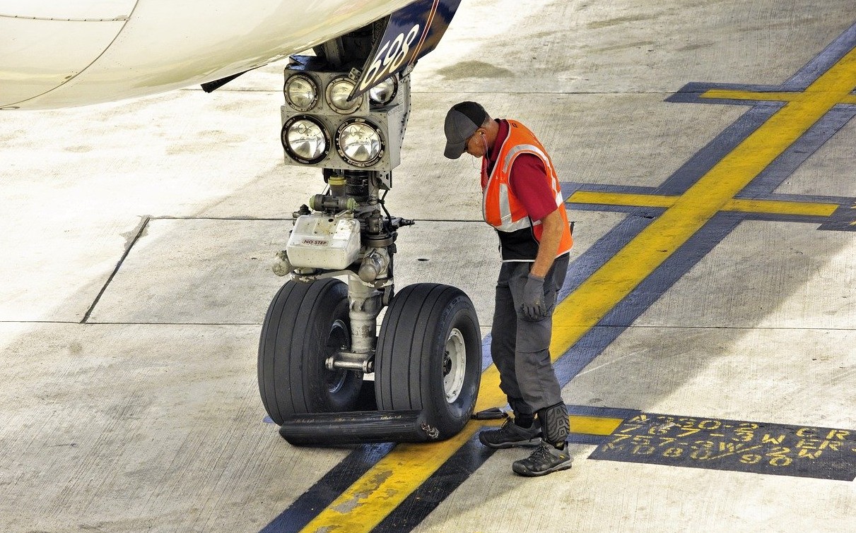 man inspecting the landing gear of a plane
